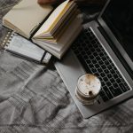 The Art of Drawing Readers In: Your attractive post title goes here A cozy home office setup featuring a laptop, open notebooks, and a cup of coffee, promoting productivity and comfort.